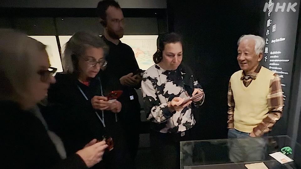 Ernest Satoru Arai, kanan, menjelaskan kemeja miliknya kepada pengunjung di Museum Memorial Perdamaian Hiroshima.