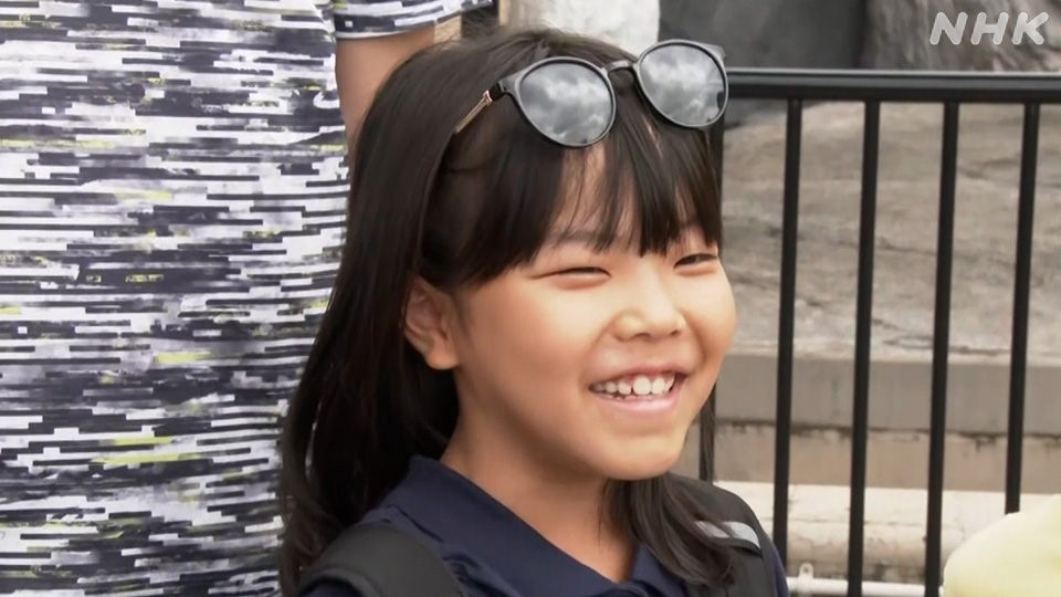 Seorang anak perempuan mengamati kawanan hewan yang sedang menikmati balok es.