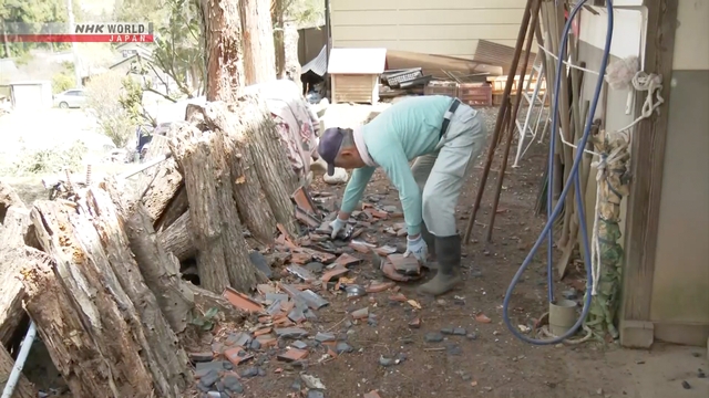 Petugas dan warga bekerja sama menutup atap rumah yang rusak dengan terpal plastik di Prefektur Nagano.