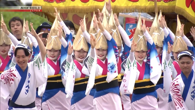 Para penari Awa Odori tampil di ruang terbuka di Kota Tokushima dengan iringan alat musik tradisional Jepang, sementara penonton menyaksikan pertunjukan dari kursi yang disediakan.