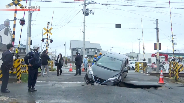 Sebuah mobil terjebak di lubang sedalam satu meter pada jalan yang amblas di dekat perlintasan sebidang kereta api.