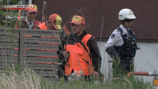 Petugas kepolisian dan pemburu lokal melakukan pencarian beruang di kawasan hijau dekat permukiman di Toyama.