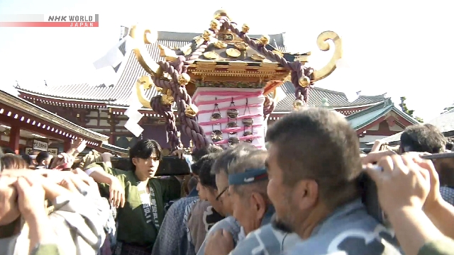 Rombongan warga memikul mikoshi atau kuil portabel melewati gerbang Kaminari-mon dalam parade Sanja Matsuri di Asakusa, Tokyo.