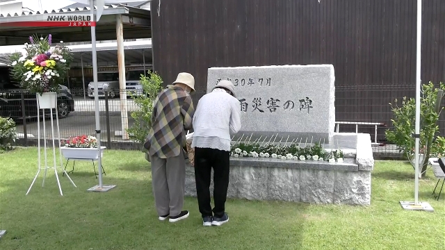 Warga meletakkan bunga dan berdoa di monumen korban bencana hujan 2018 di Prefektur Ehime, Jepang.